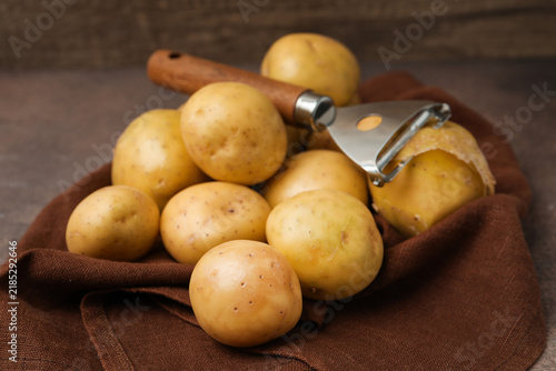 Konstfotografi Ripe young potatoes, peeler and towel on grey table, closeup
