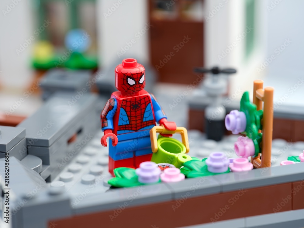 Fototapeta premium Tambov, Russian Federation - August 23, 2026 Lego Spiderman minifigure with a green watering can next to flower bed on a rooftop garden.