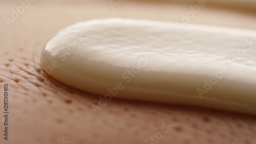 Slow motion tracking pan of cream spreading across skin close up macro surface for skincare application