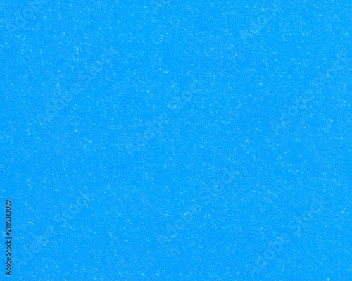 Light-blue surface of hard paper material with white inclusions, background, texture. Backdrop of blue cardboard surface. Blue wall. Faded paper surface of bright blue color. Old rough backdrop