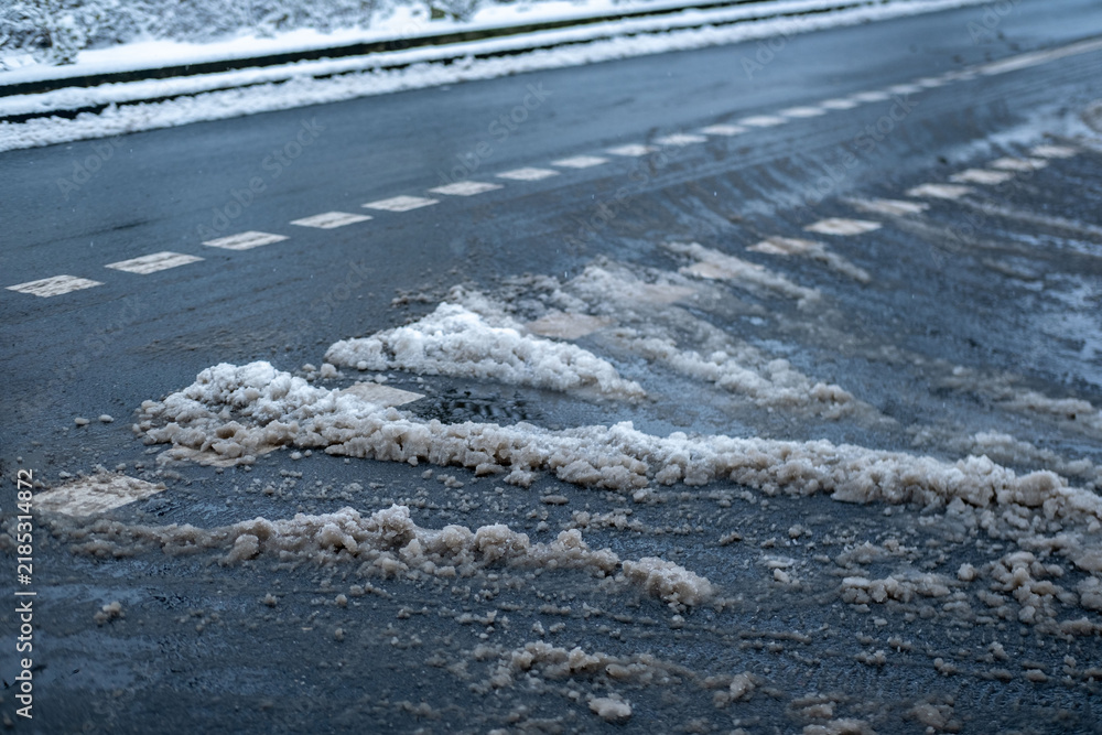 Obraz premium Deep tire tracks in melting snow, street in city, pavement after heavy snowfall, wet snow melts, slush and mud impede movement pedestrians and vehicles, traffic safety, work of public utilities