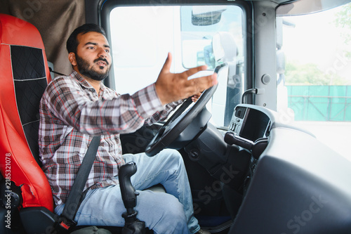 Cuadro en lienzo Truck driver gesticulating while explaining inside cabin