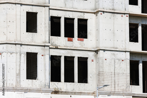 Картината върху платно Unfinished concrete multi-story building facade with empty windows and exposed r