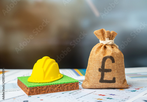 Foto British pounds money bag and a plot of land with a hard hat