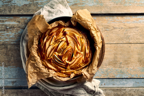 Homemade apple cake with rose pattern on a rustic wooden table