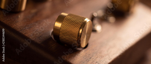 Macro Close-up of a Textured Brass Knurled Knob on Dark Walnut Wood with Cinematic Warm Lighting and Shallow Depth of Field
