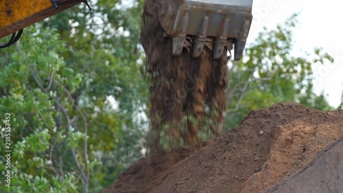 Excavator performing earthmoving operations with bucket loading and moving soil during construction site preparation, representing heavy machinery, infrastructure works and land development