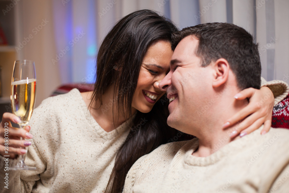 Obraz premium Laughing couple embracing with sparkling wine in Christmas close up