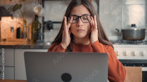 Young Latina remote worker experiencing eye strain after long hours on her laptop at home, highlighting screen fatigue, digital work stress, and wellness concerns.