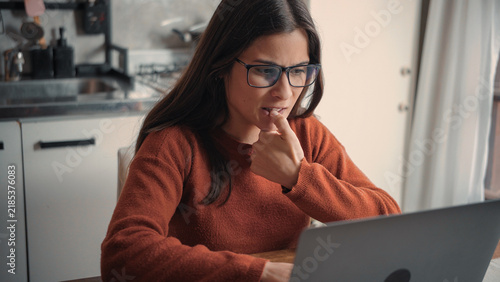 Foto Young Latina remote worker biting her nails anxiously while using a laptop at home, highlighting work stress, anxiety, professional pressure, and digital challenges