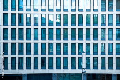 Modern office building facade with rows of repeating glass windows in a pattern.