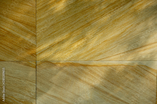 Close-up texture of yellow and beige sandstone tiles with natural grain pattern.