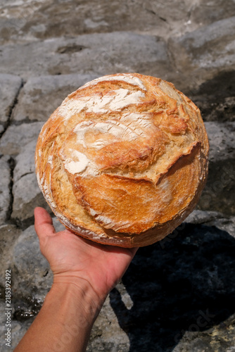 Hand Holding a Rustic Artisan Bread Loaf Outdoors
