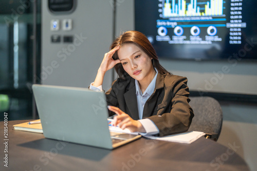 Asian female employee suffering from heavy job pressure and severe headache at office desk, Stressed business woman massaging temples experiencing work overload, Corporate mental health care concepts