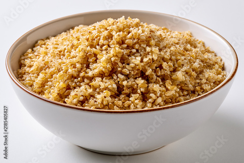 Bowl of bulgur wheat on a plain surface ready for cooking