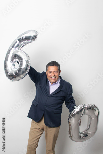 60-year-old Latino man with a dark skin displays 60 shaped balloons to celebrate his birthday and his entry into his old age