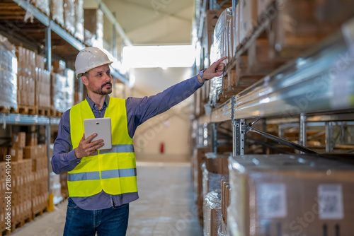Fotografie Logistics worker checking inventory in warehouse with tablet