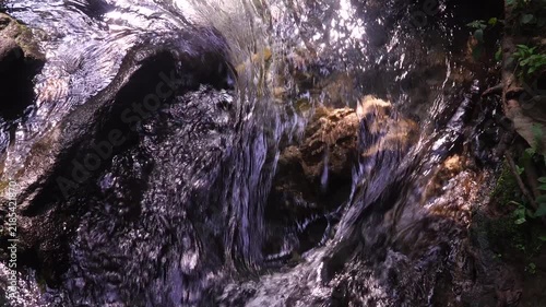 Fast Flowing River Water Rushing over Rocks with Sunlight Reflection