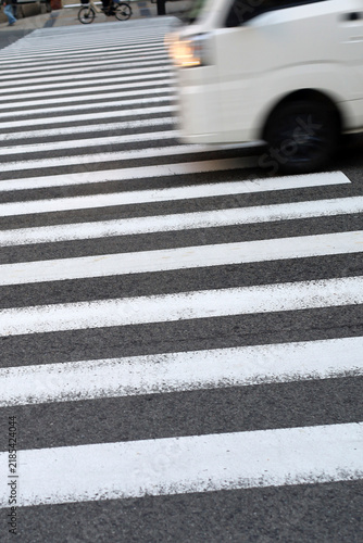 Photography White van driving quickly across marked zebra crossing.