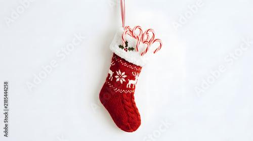 Stocking hangs against a plain transparent background filled with sweet peppermint candy canes.