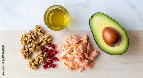 Healthy food ingredients avocado walnuts salmon and olive oil on wood