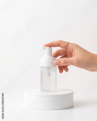 Hand Pressing Foam Pump Bottle on White Round Podium Mockup
