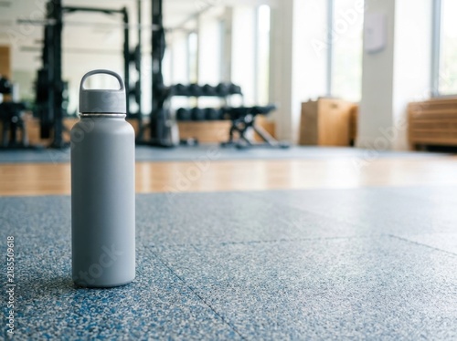 A plain reusable water bottle standing tall far to the left of a...