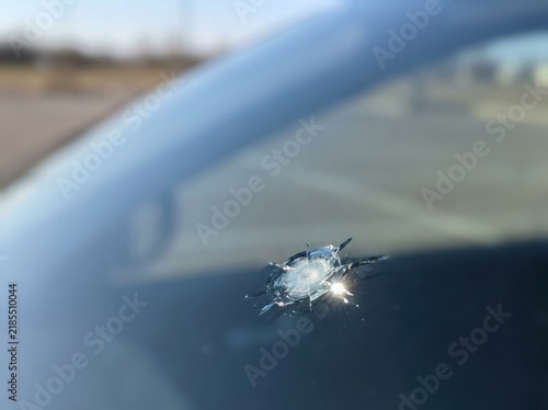 Small chipped stone impact on vehicle glass forming a tiny...