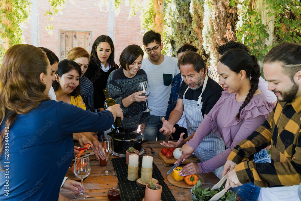 Obraz premium Group of Latin American Adult Students With Teacher Preparing recipe ingredients in Cookery Class in Mexico. Hispanic people multi generations learning together to cook in a terrace outdoors
