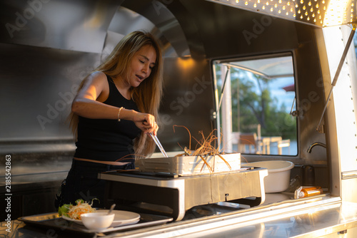 A woman is grilling food from a food truck.