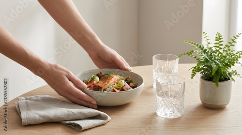A woman serves a fresh bowl of salad on a wooden table at home.