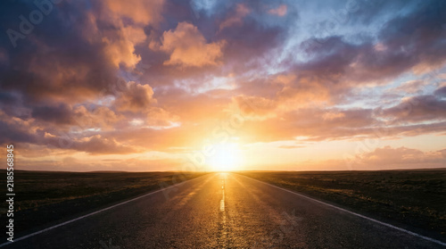 Empty road, sunset sky, horizon line, dramatic cloud, bright sunlight, open landscape
