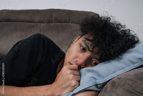 Obraz na płótnie Depressed Young Man Lying On Sofa Resting His Head On Pillow