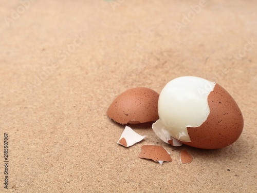 Canvastavla Close up of a partially peeled hard boiled brown egg with shell fragments on a wooden background