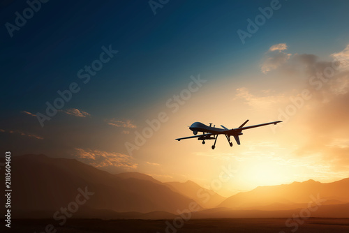 Unmanned Reconnaissance Drone Aircraft Flying Low Above Mountain Peaks Against Warm Golden Sunset Sky