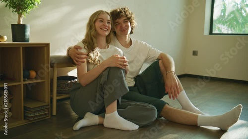 Couple sitting on the floor in a room with natural light and plants while sharing a moment together