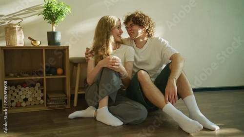 Couple enjoying time together on the floor in a cozy living room with sunlight streaming in from a window