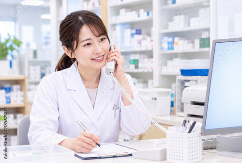 薬局で電話対応をする女性薬剤師