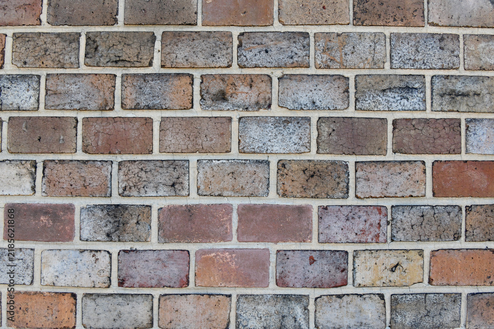 Obraz premium A full-frame view of a weathered brick wall featuring varied tones of red, grey, and brown bricks set in light mortar from the historic fortress walls in Prague.