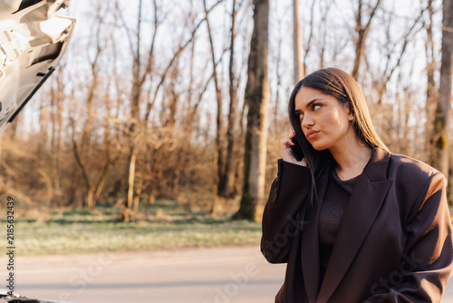 Fotografie Woman calling roadside assistance after car breakdown