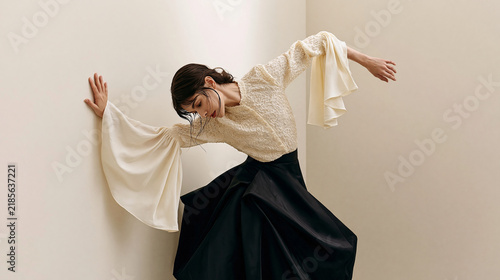 Contemporary Fashion Model in Elegant Flowing Sleeves and Black Skirt Posing in Minimalist Architectural Interior