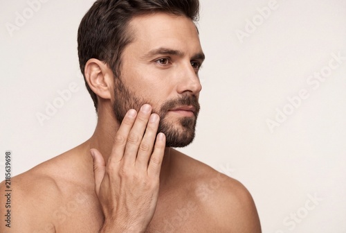 Portrait of a handsome man touching his beard isolated on white background