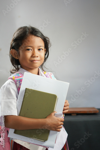 Konstfotografi Young schoolgirl holding books in classroom