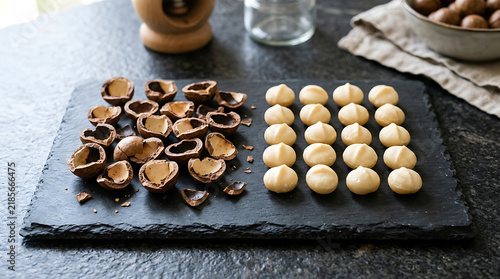 Shelled and unshelled macadamia nuts arranged on a dark slate board