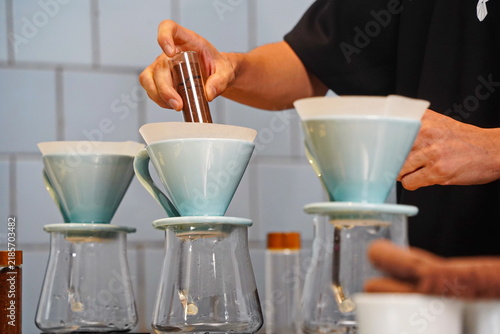 Foto The barista brews specialty coffee using a filter and a glass server