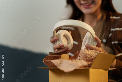 Happy woman unboxing new wireless headphones received from online shopping delivery