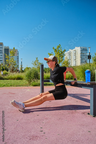 The girl is doing sports on the street playground.