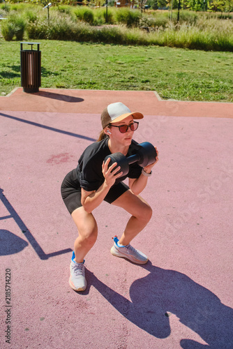 The girl is doing sports on the street playground.