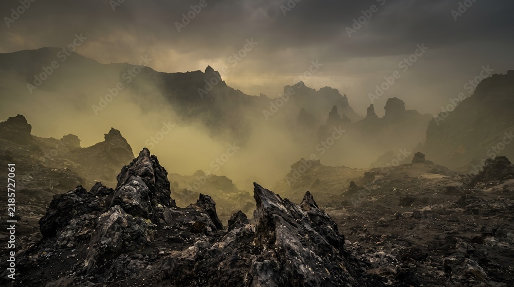 Obraz premium Dramatic landscape with rocky mountains shrouded in heavy fog at sunrise.