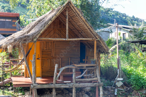 Fotografie Rustic bamboo hut with a thatched roof nestled in a lush green countryside